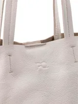 Cartera tipo shopper de cuero en color crudo, sin forro y con terminaciones al corte. Cuenta con gran capacidad y un bolsillo interior con cierre.