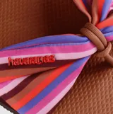 Sandalias Havaianas modelo You St Tropez con base de goma marrón y tira superior de tela con diseño de lazo a rayas multicolor.
