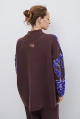 Buzo de tejido de punto con diseño floral en contraste, cuello redondo y mangas largas. Presenta una textura suave y un corte holgado.