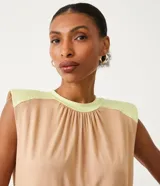 Blusa sin mangas color beige con detalle en los hombros y cuello color verde claro.