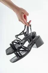 Sandalias de cuero negro con tiras finas cruzadas, taco cuadrado y hebilla lateral.