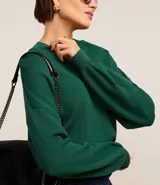 Blusa de mangas largas color verde esmeralda, confeccionada en tejido de punto con viscosa sostenible, cuello redondo y rib en puños y bajo.