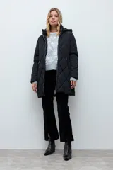Campera acolchada de corte largo con diseño capitoneado en forma de rombos, cierre frontal con cremallera y capucha integrada.