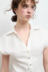 Camisa color beige claro de lino, con cuello clásico, abotonada al frente y sin mangas.