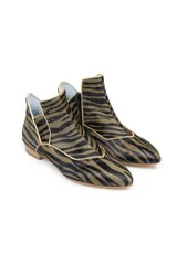 Botines de piel con diseño original, confeccionados artesanalmente en España. Presentan un estampado animal print en tonos verde y negro, con una estructura de piezas superpuestas y una pieza frontal elevada que estiliza el empeine. Cuentan con cierre lateral, interior forrado en piel y suela de cuero.
