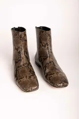 Botas cortas de gamuza color marrón, con punta cuadrada y cierre lateral. Diseño minimalista con costura central vertical.