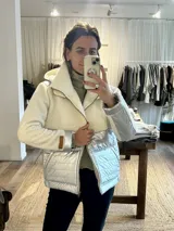 Campera con mitad superior de paño de lana color crudo y mitad inferior impermeable plateada. Forrada con peluche, con cierre delantero, bolsillos frontales y capucha desmontable.