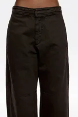 Pantalón de corte barrel y tiro medio, confeccionado en mezcla de algodón. Presenta cierre frontal oculto con botón y cremallera, bolsillos laterales y costadillos que estructuran la silueta.