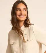 Camisa color fucsia de tejido airflow, con cuello camisero, mangas cortas con pliegues, cierre frontal con botones metalizados y bolsillos con solapa en el pecho.