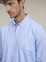 Camisa celeste de manga larga con cuello abotonado y bolsillo en el pecho.