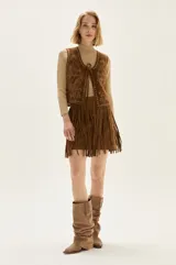 Chaleco de cuero color camel con bordados decorativos, tachas metálicas en los bordes y cierre frontal mediante lazos.