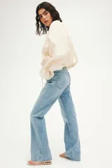 Pantalón jean de tiro alto y corte bootcut, confeccionado en denim de algodón con ligera elasticidad. Presenta diseño clásico de cinco bolsillos, cierre frontal con botón y cremallera, y perneras ligeramente acampanadas en el bajo.