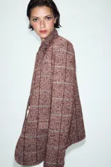 Blazer de lana con diseño de cuadros, cuello subido, manga larga, bolsillos delanteros y cierre frontal cruzado con un botón.