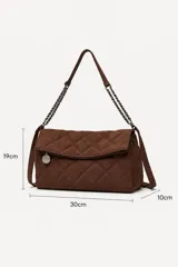 Cartera tipo bandolera de color negro con diseño acolchado en patrón de rombos. Cuenta con una solapa frontal, correa de hombro que combina material textil con cadena metálica oscura y un dije circular decorativo.