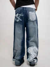 Jean de denim azul de corte regular fit y tiro alto, con efecto desgastado. Presenta estampados en color blanco: un diseño abstracto en el bolsillo trasero izquierdo, una cuadrícula en el bolsillo trasero derecho y un tigre en la parte inferior de la pierna derecha.