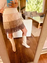 Minifalda tejida con cintura elástica y flecos en tres tonos: crudo, beige y marrón.
