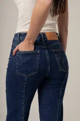 Jean de denim negro, tiro alto y corte recto, con costuras verticales decorativas en el frente.