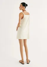 Vestido corto de corte recto y silueta holgada, con escote en V y breteles finos con detalle de argollas metálicas en los hombros.