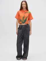 Camisa crop de viscosa con diseño estampado de autor en tonos naranja y verde, de manga corta y cuello clásico.