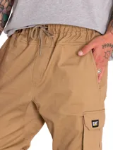 Pantalón cargo beige con múltiples bolsillos utilitarios, cintura elástica y puños elastizados en los tobillos.