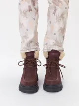 Borcegos de caña baja con diseño robusto, confeccionados en una combinación de gamuza y cuero sintético en tonos verde oliva. Presentan suela track de goma dentada en color suela, cordones al tono con ojalillos amarillos y cuello acolchado para mayor confort.