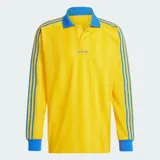 Camiseta de manga larga Adidas Originals, de corte holgado y color amarillo con rayas verticales sutiles en tono más oscuro y detalles en azul en cuello polo, puños y las clásicas franjas en las mangas. Cuenta con el logo bordado en el pecho.