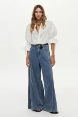 Camisa blanca de manga larga abullonada con detalle de punto smock en los puños y cordones para atar. Presenta cuello clásico y cierre frontal de botones.