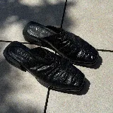 Zueco de cuero color marrón con diseño fruncido en la parte delantera y taco bajo.