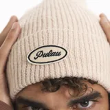 Gorro tipo beanie tejido en punto acanalado, con parche ovalado bordado en la parte frontal que incluye el logo de la marca.