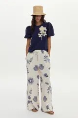Pantalón de pierna ancha, confeccionado en lino, con cintura elástica con cordón de ajuste y estampado en tonos azules sobre base cruda.