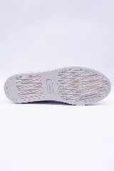 Championes de cuero color marrón con diseño perforado en los laterales, cordones al tono y suela de goma blanca.