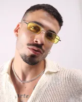 Lentes de sol rectangulares con marco plateado y cristales amarillos.