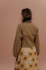Chaqueta verde militar de corte clásico, cuello mao y cierre frontal con botones. Cuenta con bolsillos ojal en el pecho y mangas largas.