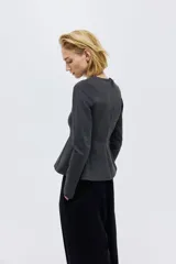 Blusa de manga larga confeccionada en punto grueso, con diseño entallado, escote redondo y cierre oculto en la espalda. Presenta costuras frontales que estilizan la figura y un detalle de peplum con vuelo en la cintura.
