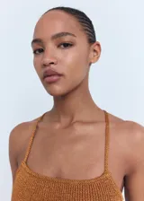 Top de punto con acabado de lúrex en color bronce, de diseño entallado, cuello escotado y tirantes finos que se cruzan en la espalda.