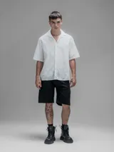 Camisa blanca de manga corta, con cuello abierto y calce oversize. Confeccionada en algodón bordado tipo broderie con diseño floral.