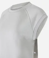 Remera deportiva de mujer color blanco hueso, con cuello redondo y mangas cortas tipo raglán con pespuntes visibles. Presenta un ruedo inferior más ancho y ajustado.