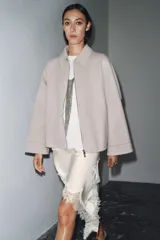 Chaqueta de lana en color beige, con cuello solapa, cierre frontal con cremallera metálica, mangas largas con corte evasé y bajo asimétrico.