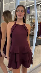 Vestido corto bordó con escote halter, espalda descubierta y falda de volantes en niveles.