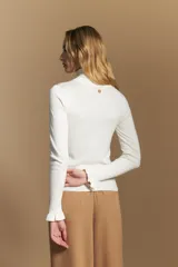 Polera de tejido fino color negro, con cuello alto y mangas largas con terminación sutilmente fruncida. Diseño ajustado al cuerpo.