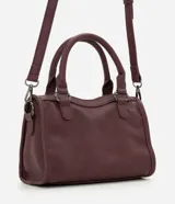 Cartera satchel Satinato de color negro, confeccionada en poliuretano. Cuenta con asas de mano fijas, correa larga removible, bolsillos frontales con cierre, tachas metálicas decorativas y tiras colgantes.