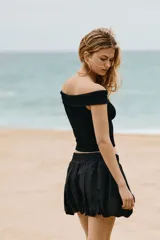 Top negro de punto acanalado de algodón, corte ajustado, con hombros descubiertos y escote ancho doblado.