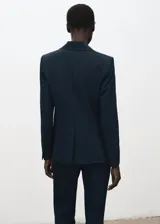 Blazer ajustado color azul marino, con cuello en V, solapas con muesca y cierre frontal de botones. Cuenta con bolsillos delanteros con solapa y bolsillo ribeteado en el pecho, mangas largas con puños abotonados, abertura en la parte trasera del bajo y forro interior.