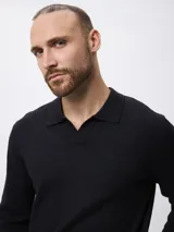 Sweater de punto color negro, con cuello polo y escote en V, de manga larga y diseño ajustado.