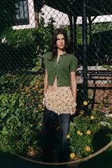 Chaqueta de punto de textura peluda en color verde, con cuello redondo, manga corta y cierre frontal con botones a tono.