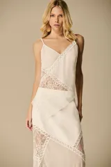 Blusa color crema con breteles finos, escote en V y recortes asimétricos de encaje.