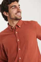 Camisa de manga larga confeccionada en una mezcla de algodón y lino, con cuello abotonado, bolsillo frontal en el pecho y cierre de botones.