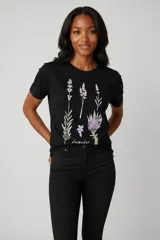 Remera de algodón color beige con estampado floral en tonos azules en el centro del pecho y detalle de texto manuscrito.