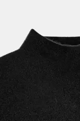 Top de punto color verde militar, con cuello subido y manga sisa. Presenta apliques dorados en los laterales y un bajo asimétrico.