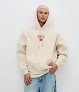 Buzo con capucha de corte boxy, color beige, con bolsillo canguro frontal y estampa bordada de Bob Esponja y Patricio en el pecho. Presenta puños y cintura acanalados, y cordones ajustables en la capucha.